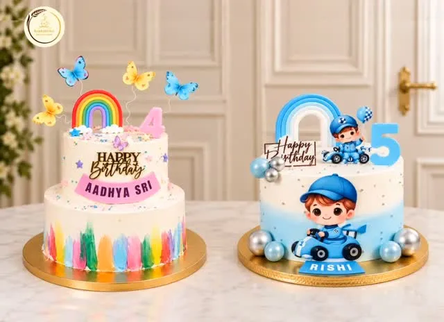 Two birthday cakes on a marble table: one with a rainbow, butterflies and the name Aadhya Sri, the other with a blue racing driver figure, a number five and the name Rishi.
